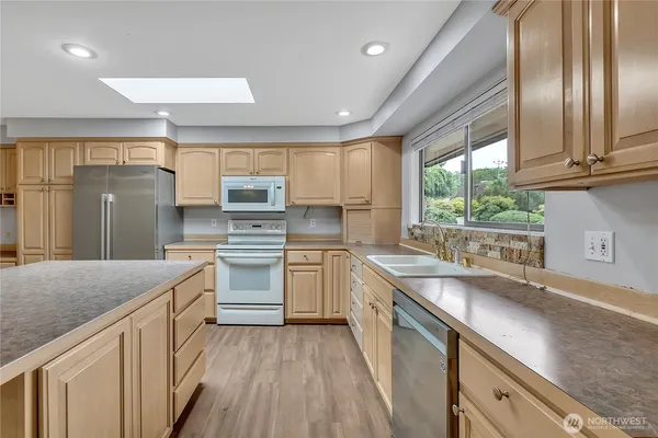 a kitchen with granite countertop stainless steel appliances a sink window and cabinets