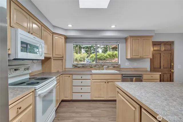 a kitchen with stainless steel appliances granite countertop hardwood floor sink stove and granite counter top