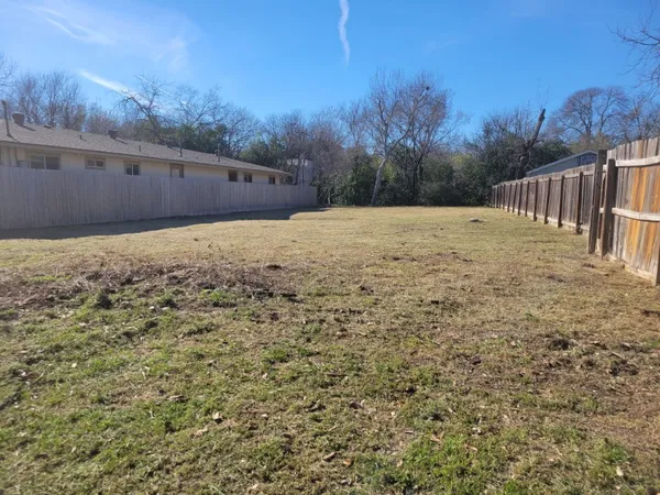 a view of a yard with wooden fence