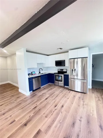 a kitchen with stainless steel appliances a refrigerator and wooden floor