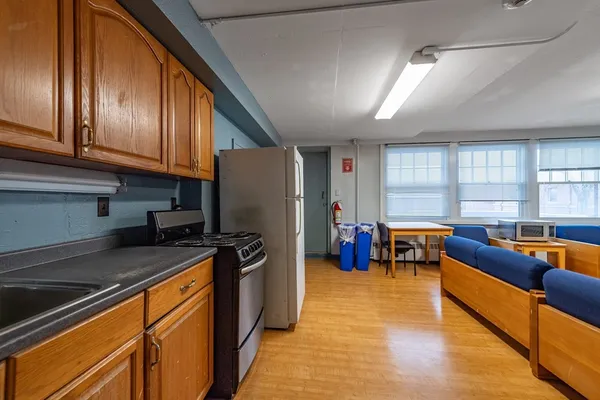 a kitchen with stainless steel appliances granite countertop a refrigerator a sink dishwasher a stove and white countertops with wooden floor