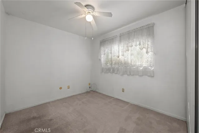 an empty room with a chandelier fan and windows