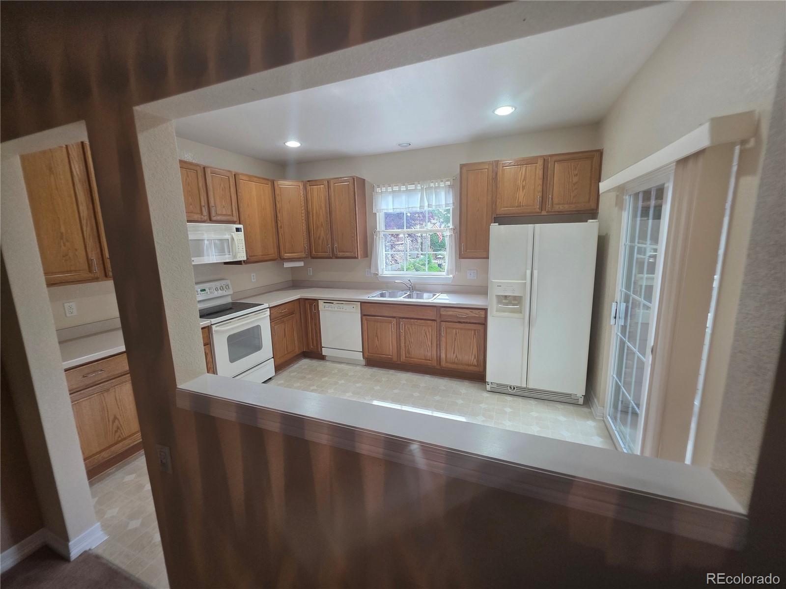 8911 Tappy Toorie Place Highlands Ranch, CO 80129 - Photo 13 of 28 a kitchen with stainless steel appliances granite countertop a refrigerator a sink a stove a microwave and island