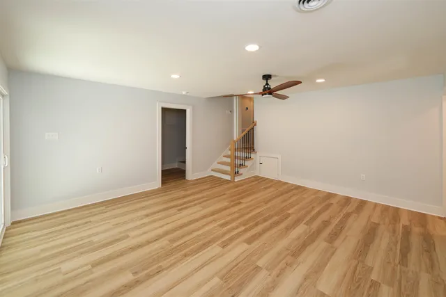 a view of empty room with wooden floor and ceiling fan