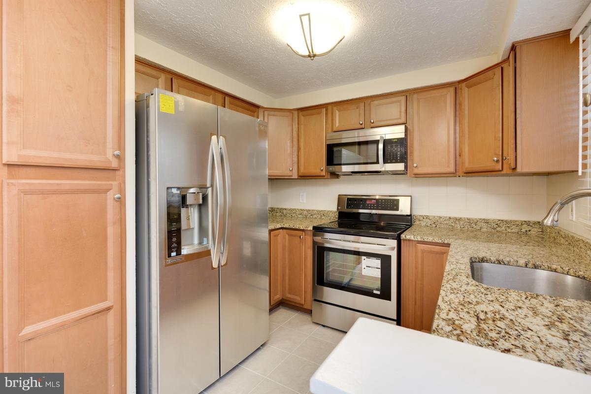 11052 Granby Court Reston, VA 20191 - Photo 5 of 28 a kitchen with granite countertop a refrigerator and a stove top oven