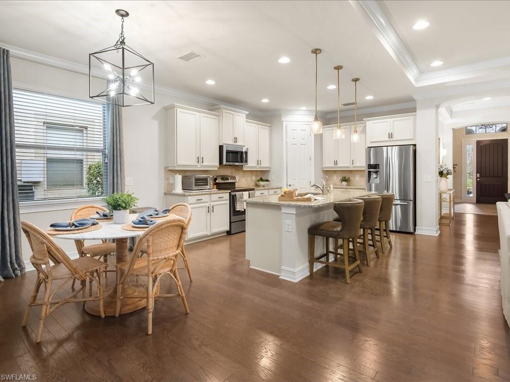 16242 Aberdeen Way Naples, FL 34110 - Photo 6 of 30 a dining room with stainless steel appliances kitchen island granite countertop a sink a stove a dining table and chairs