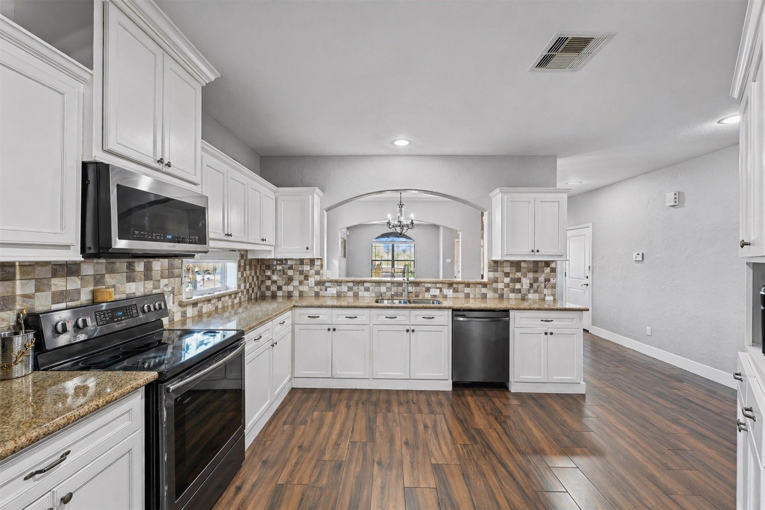 19545 Crosby Eastgate Road Crosby, TX 77532 - Photo 2 of 26 a kitchen with stainless steel appliances granite countertop wooden cabinets a stove a sink and dishwasher with wooden floor