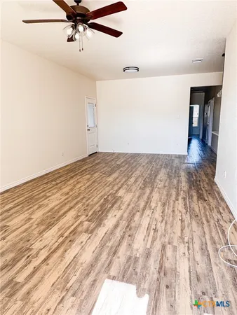 a view of a room with a ceiling fan and wooden floor