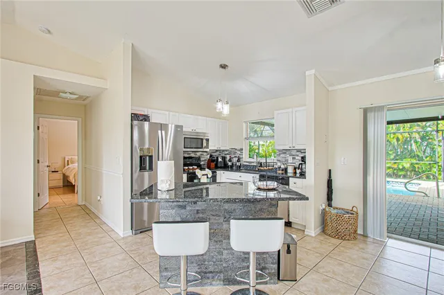 a kitchen with stainless steel appliances kitchen island granite countertop a refrigerator and a sink