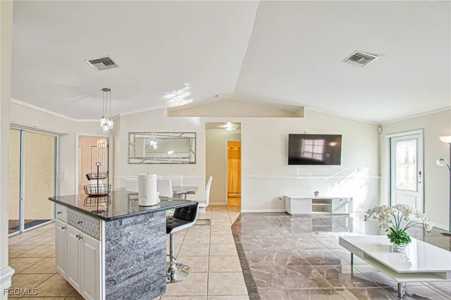 a living room with granite countertop couches a flat screen tv and kitchen view
