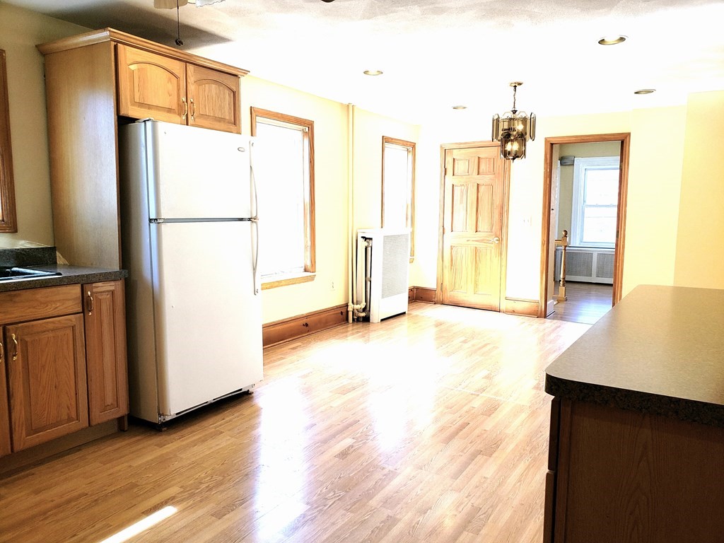 63 Irving Street Everett, MA 02149 - Photo 5 of 8 a view of a kitchen with wooden floor and a refrigerator