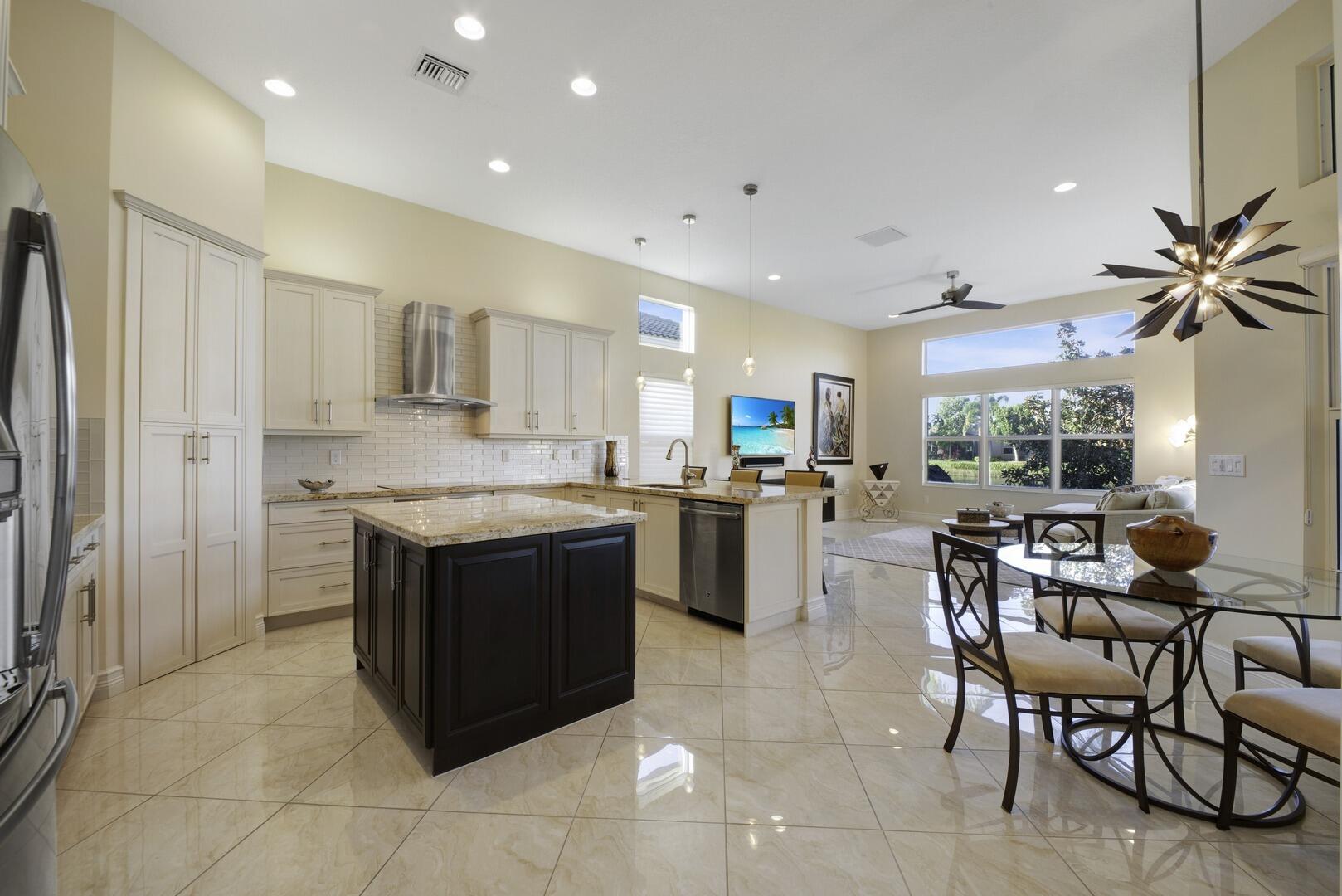 8289 Razorback Court Boynton Beach, FL 33473 - Photo 12 of 51 a kitchen with stainless steel appliances granite countertop wooden cabinets a dining table and chairs