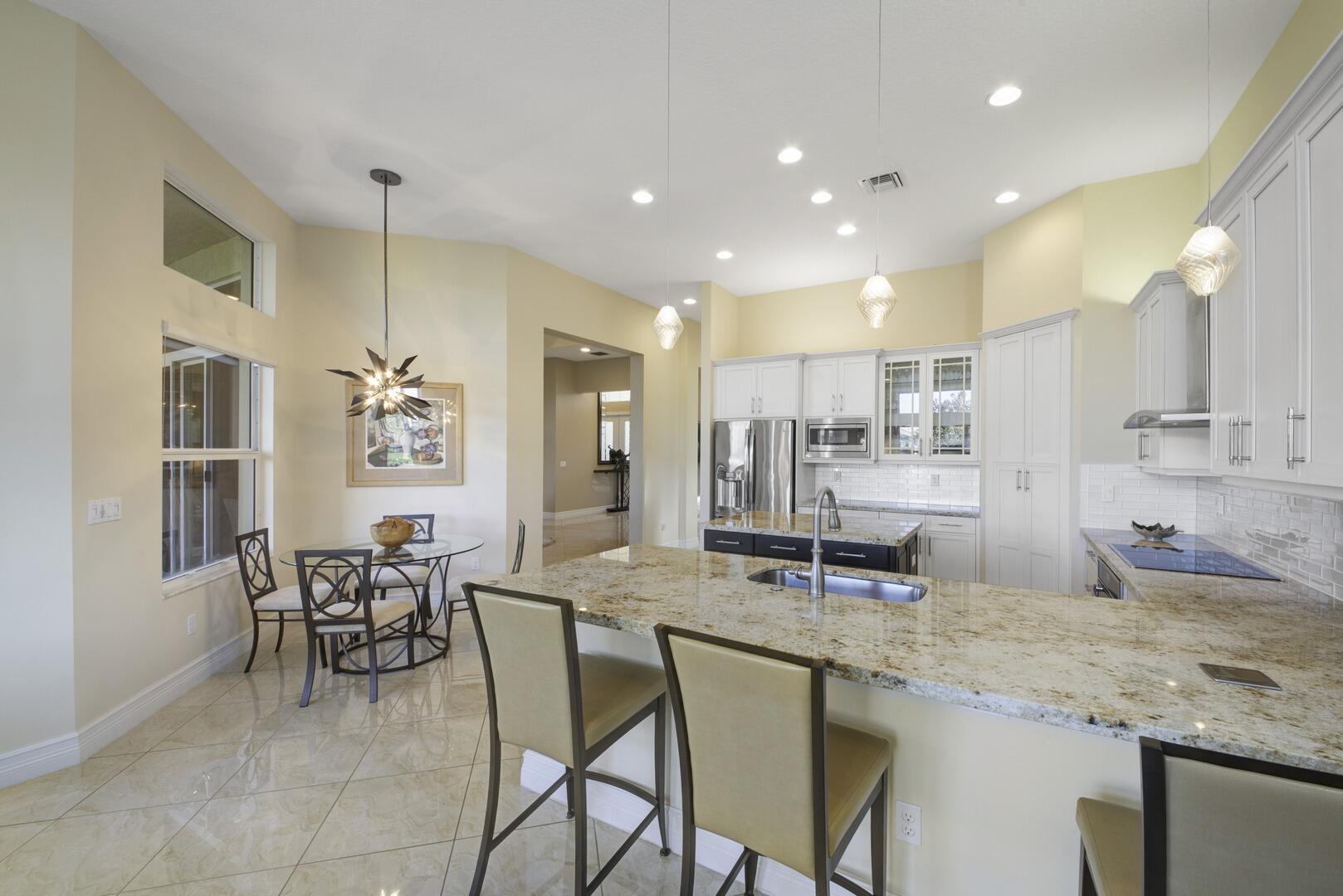 8289 Razorback Court Boynton Beach, FL 33473 - Photo 14 of 51 a kitchen with stainless steel appliances granite countertop dining table chairs and a refrigerator