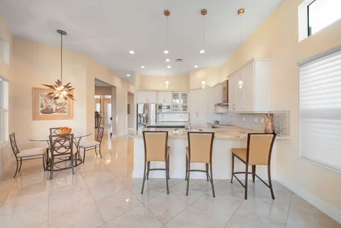 a kitchen with stainless steel appliances granite countertop dining table chairs and a refrigerator