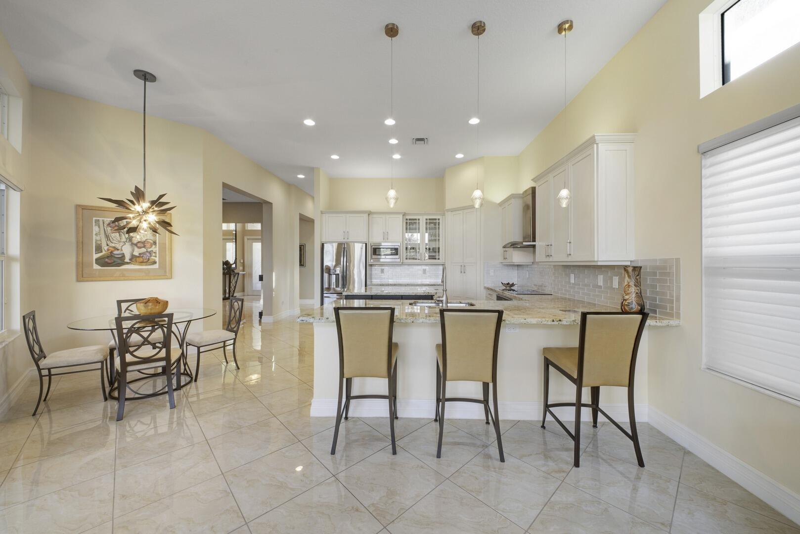 8289 Razorback Court Boynton Beach, FL 33473 - Photo 15 of 51 a kitchen with stainless steel appliances kitchen island granite countertop a table chairs and a refrigerator