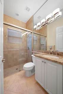 a bathroom with a granite countertop sink a toilet and shower