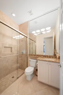 a bathroom with a granite countertop sink a toilet and a shower
