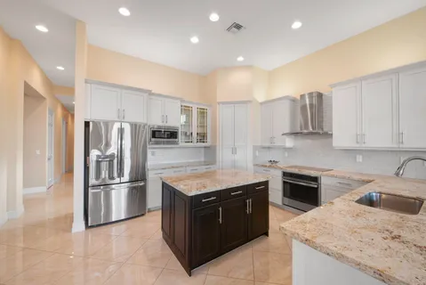 a kitchen with stainless steel appliances granite countertop a sink a stove a refrigerator and a refrigerator