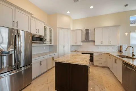 a kitchen with stainless steel appliances granite countertop a refrigerator sink and white cabinets