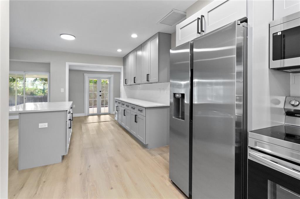 772 Palmer Road Belleair Bluffs, FL 33770 - Photo 7 of 26 a kitchen with stainless steel appliances granite countertop a refrigerator a sink a stove and white cabinets with wooden floor