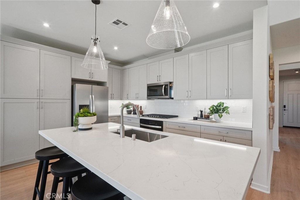 73525 Raphael Drive Palm Desert, CA 92211 - Photo 9 of 41 a kitchen with stainless steel appliances a white table chairs and a refrigerator