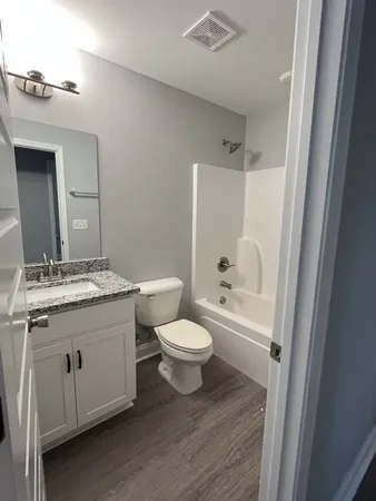 a bathroom with a granite countertop toilet a sink and a mirror