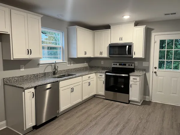 a kitchen with stainless steel appliances granite countertop a stove a sink and a microwave
