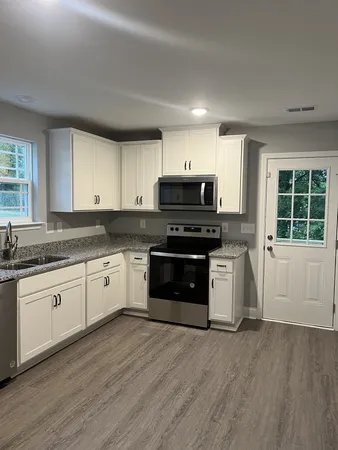 a kitchen with granite countertop a stove a sink and a microwave