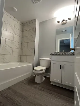 a bathroom with a granite countertop sink toilet a mirror and bathtub