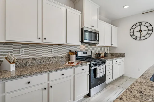 a kitchen with granite countertop white cabinets white stainless steel appliances and a sink