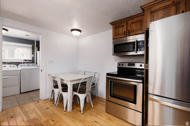 197 West 100 South Redmond, UT 84652 - Photo 13 of 41 Kitchen featuring stainless steel appliances, washing machine and clothes dryer, a textured ceiling, and light wood finished floors
