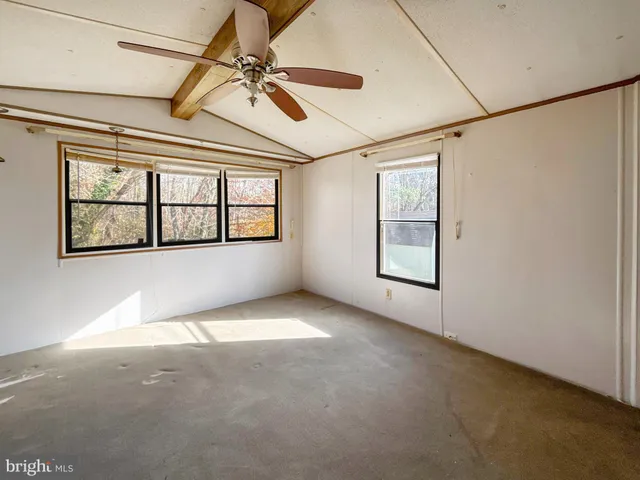 an empty room with windows and ceiling fan
