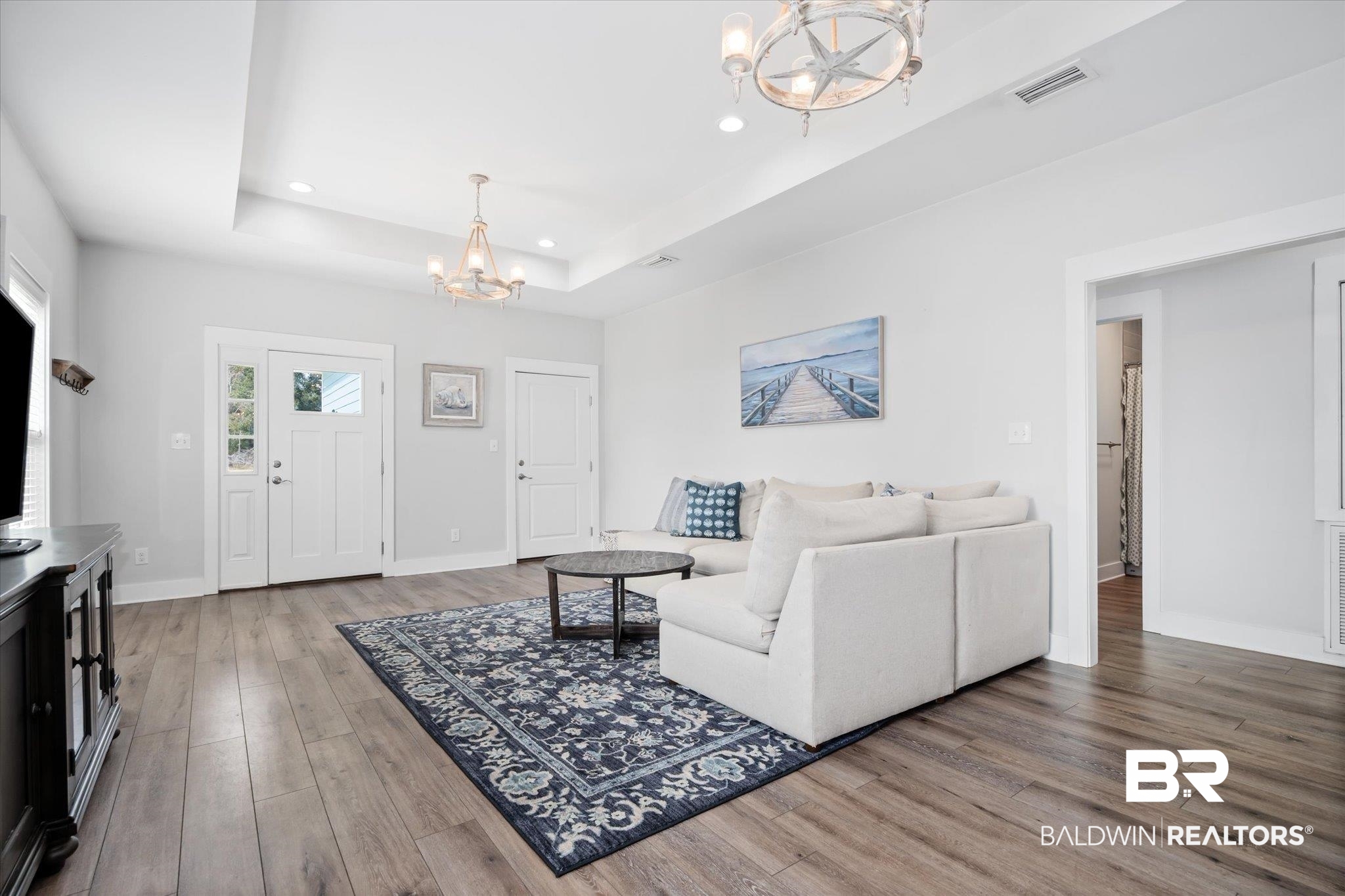 8056 Carmel Circle Foley, AL 36535 - Photo 5 of 28 Living room featuring an inviting chandelier, hardwood / wood-style floors, and a tray ceiling