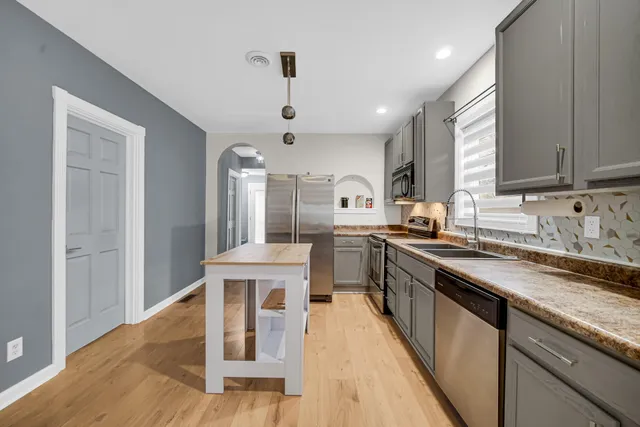 a kitchen with stainless steel appliances granite countertop a sink stove and wooden floor