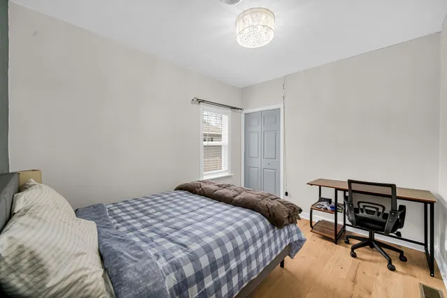 a bedroom with a bed a chair and a chandelier