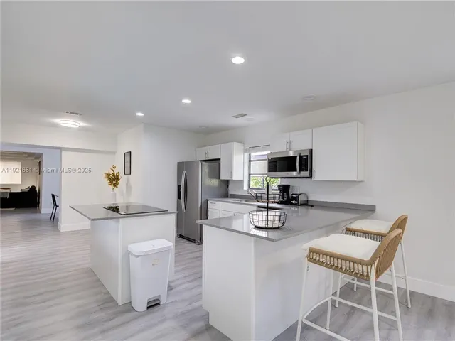 a living room with furniture a flat screen tv and kitchen view