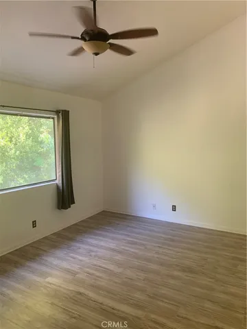 a view of an empty room with wooden floor and a window