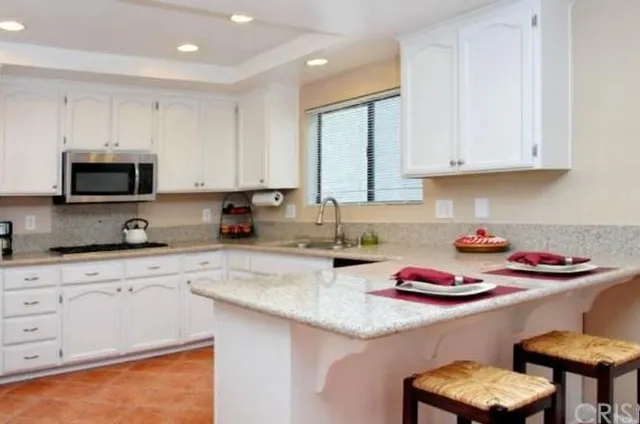 a kitchen with stainless steel appliances granite countertop a sink a stove and white cabinets