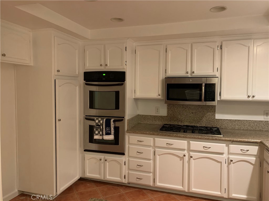 5246 Calderon Road Woodland Hills, CA 91364 - Photo 8 of 50 a kitchen with white cabinets and black appliances