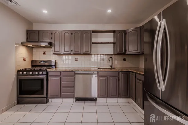 a kitchen with stainless steel appliances granite countertop a refrigerator sink and stove