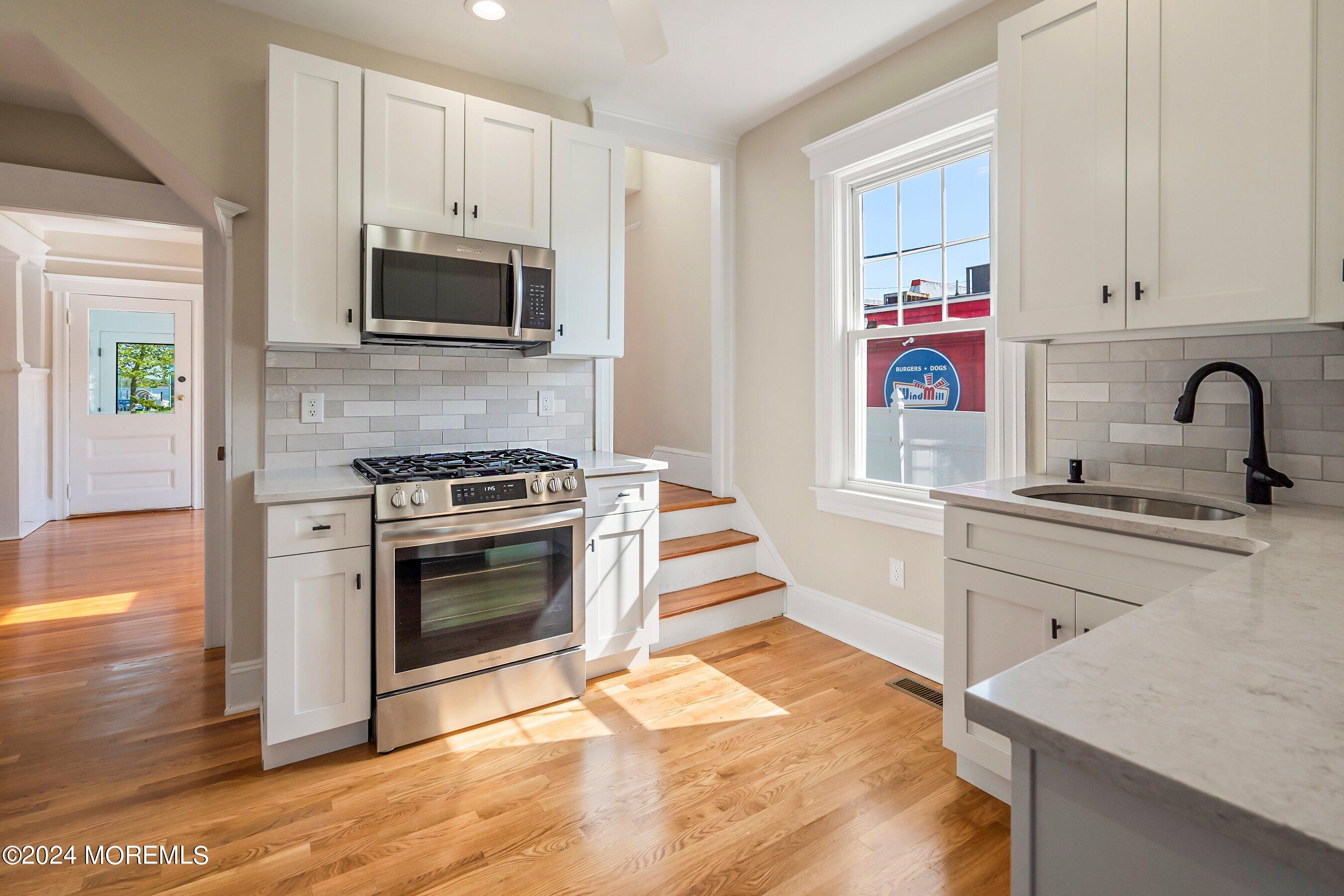 1202 River Road Belmar, NJ 07719 - Photo 14 of 32 a kitchen with stainless steel appliances white cabinets a stove a sink and a microwave