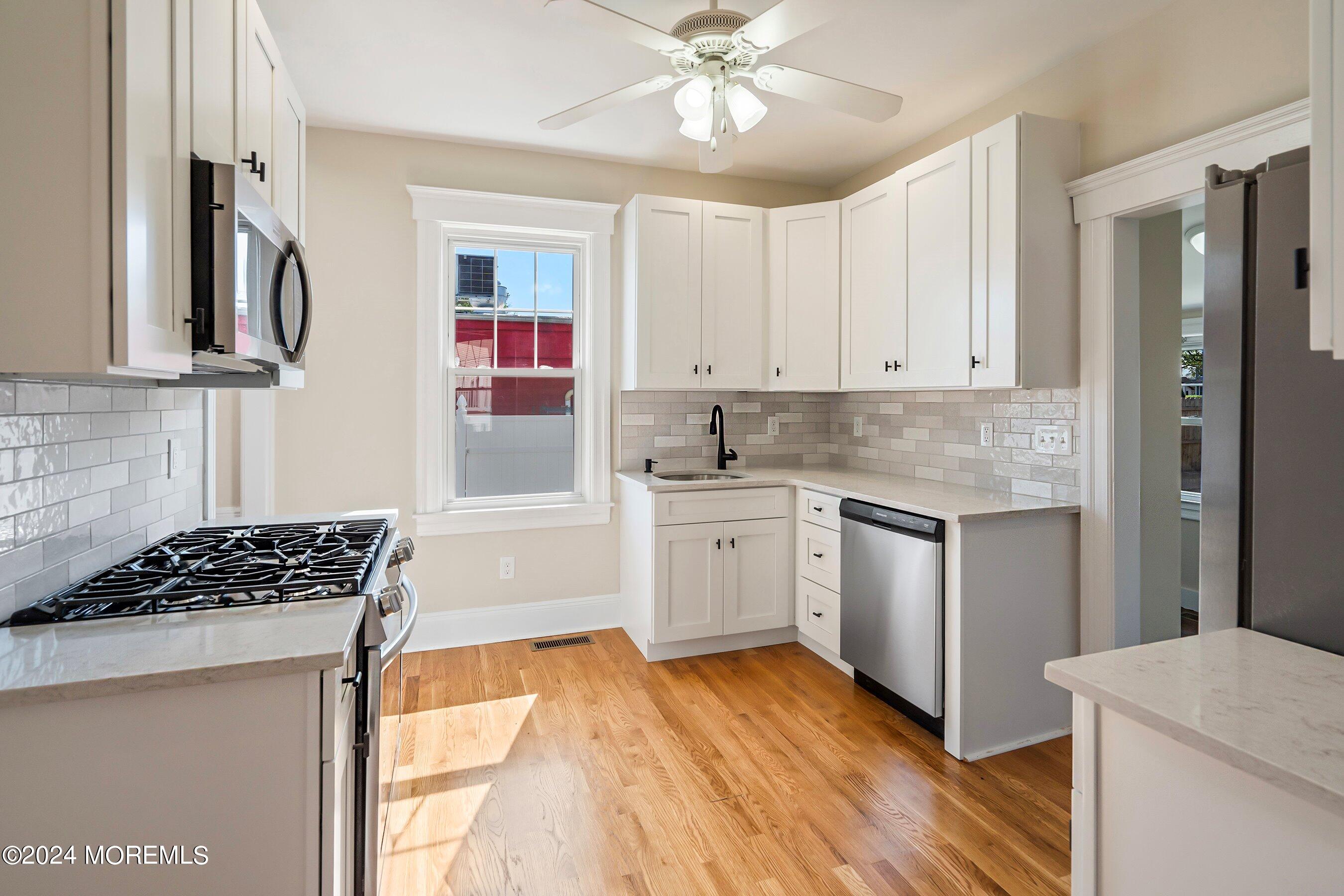 1202 River Road Belmar, NJ 07719 - Photo 15 of 32 a kitchen with granite countertop a stove a sink dishwasher and a refrigerator with wooden floor