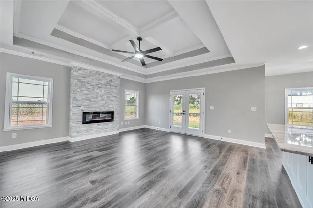 an empty room with wooden floor fireplace and windows