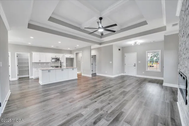 a view of open kitchen with white cabinets and refrigerator