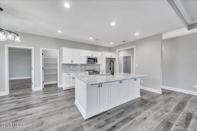a large kitchen with stainless steel appliances granite countertop a lot of counter space and wooden floors