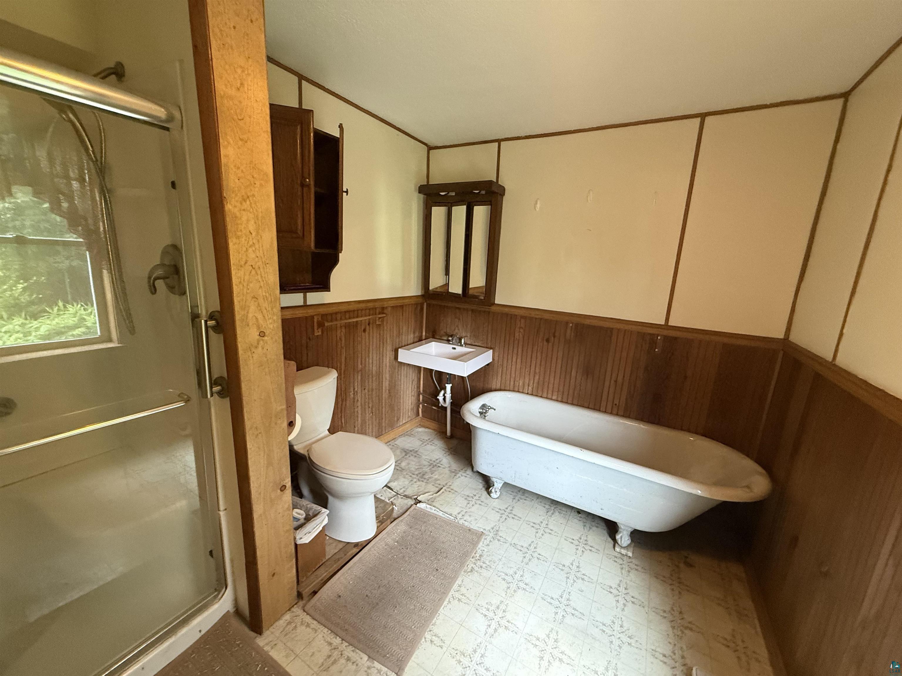 3541 Bent Trout Lake Road Barnum, MN 55707 - Photo 22 of 41 Bathroom featuring a shower enclosure with a glass door, a clawfoot bathtub, a wall-mounted sink, and a toilet