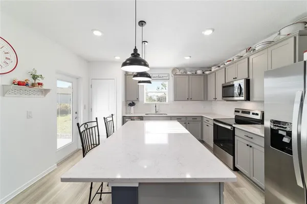 a kitchen with stainless steel appliances kitchen island granite countertop a sink a stove and chairs