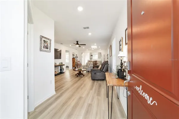 a view of a hallway to a livingroom with wooden floor and furniture