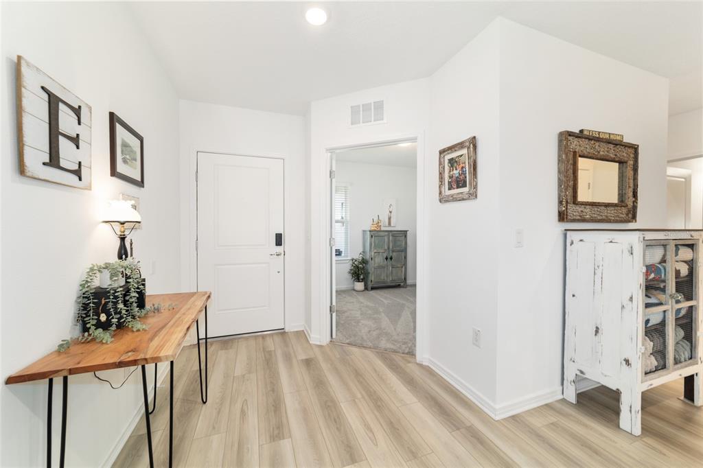 8392 Southwest 54th Street Ocala, FL 34481 - Photo 5 of 59 a view of a hallway to a livingroom with wooden floor and furniture