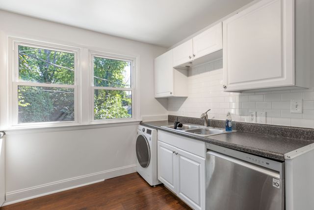 a kitchen with stainless steel appliances granite countertop white cabinets a sink a stove a window and a counter top space